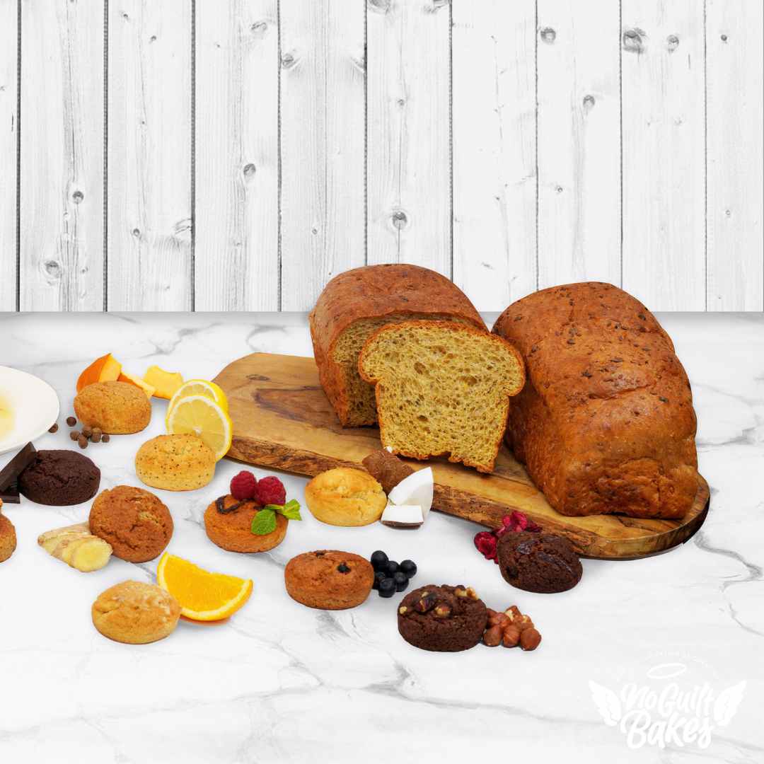 A variety of No Guilt Bakes' Treat Yo Self Bundle | Stay on Track | Gift low-carb breads and pastries are beautifully displayed on a wooden cutting board.