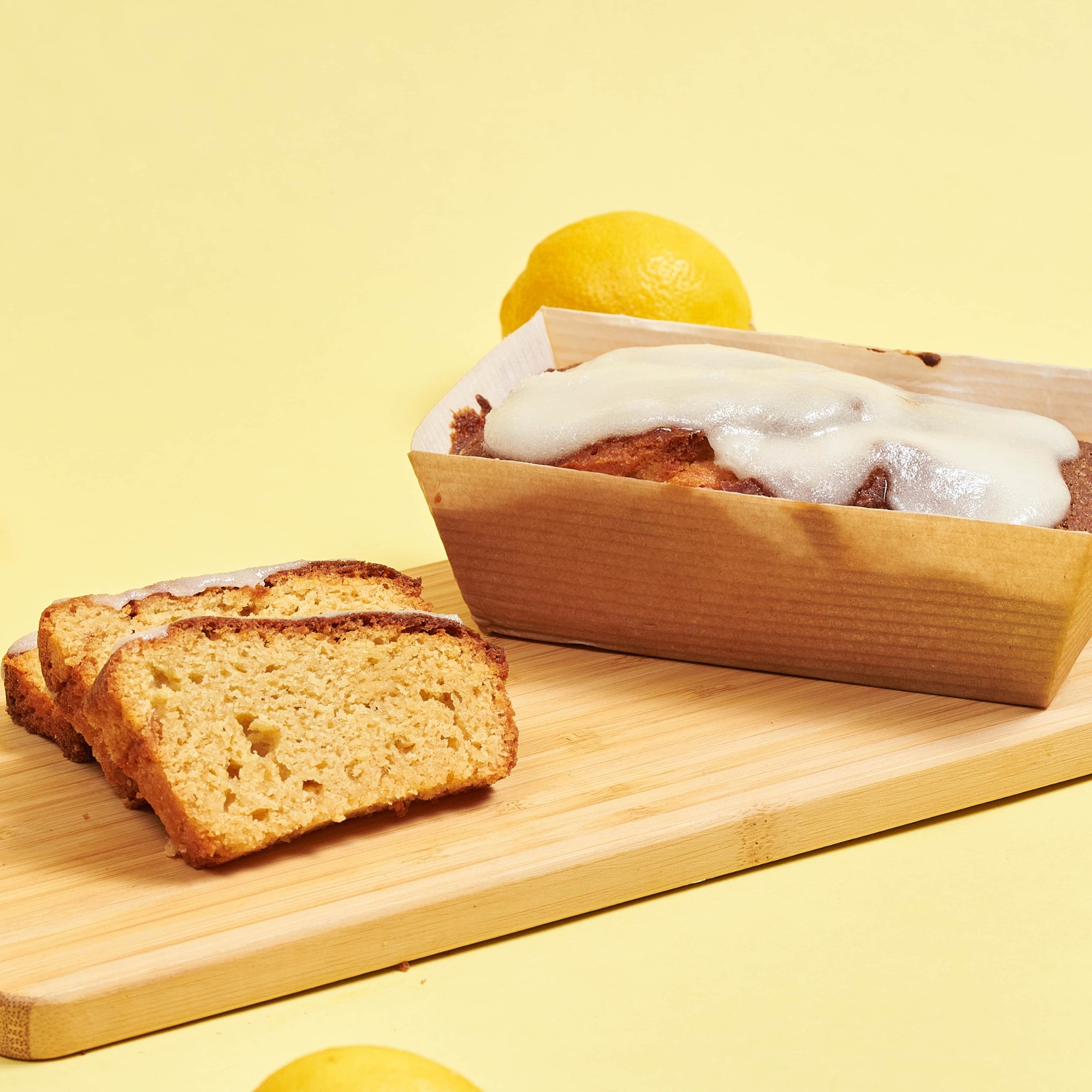 A slice of lemon bread on a wooden cutting board.