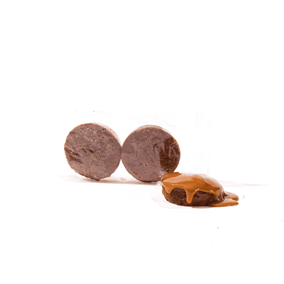 A Sticky Toffee Keto Cake Bite | Limited Edition by No Guilt Bakes, with a piece of chocolate and a piece of caramel on a white surface, ideal for those who prefer a no-added sugar alternative or are following a keto diet. Perfect as sticky toffee treats.